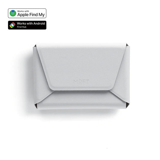 A light gray envelope-style wallet or card holder with a flap closure, shown from above on a white background. Small compatibility badges in the top-left indicate Apple Find My and Android Find Hub support.