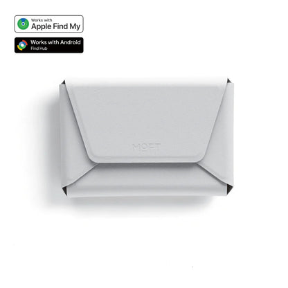 A light gray envelope-style wallet or card holder with a flap closure, shown from above on a white background. Small compatibility badges in the top-left indicate Apple Find My and Android Find Hub support.